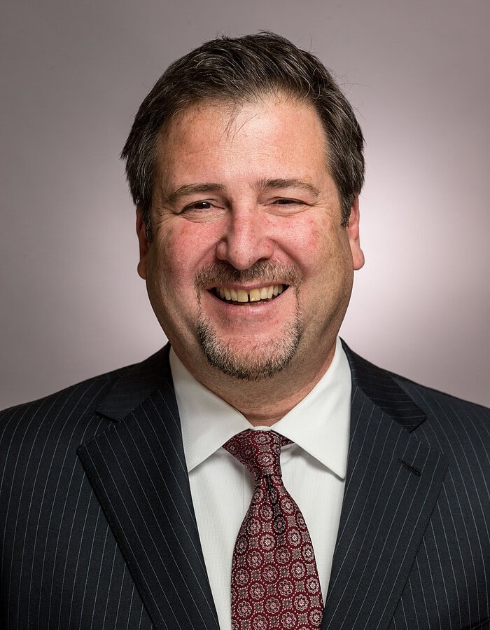 Smiling male executive in a pinstripe suit and red patterned tie.