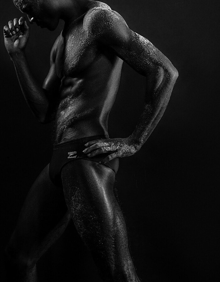 Side view of a male model with one hand on his hip in black-and-white