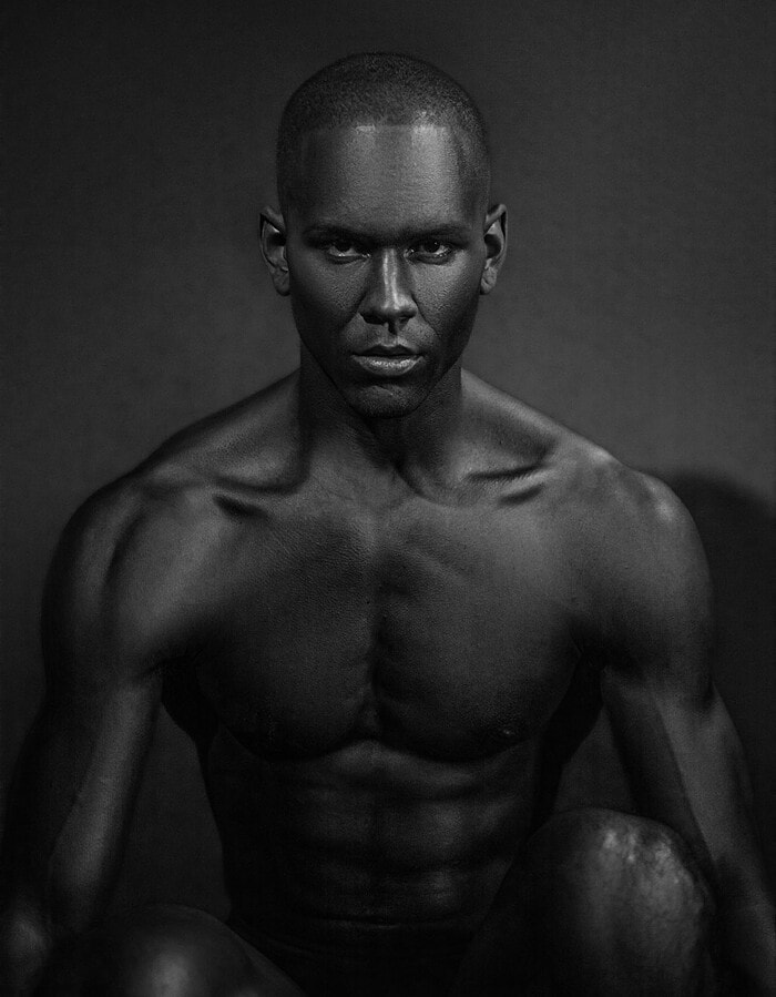 Male model leaning forward in a dark frontal black-and-white portrait
