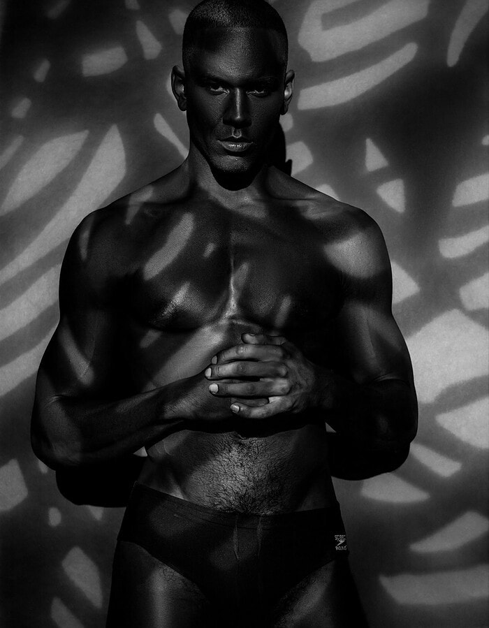 Male model facing forward beneath abstract projected shadows