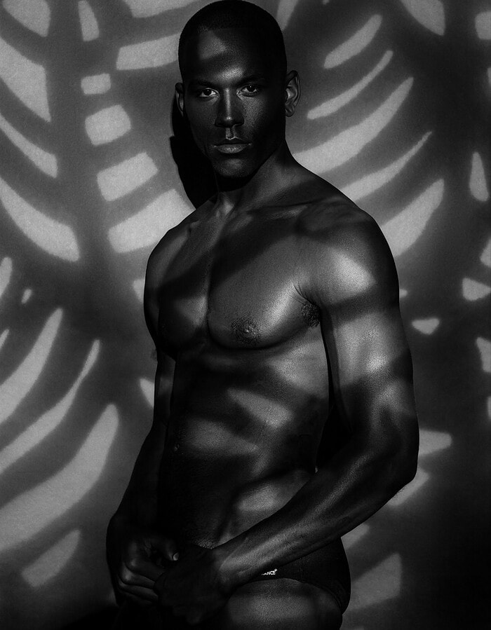 Three-quarter portrait of a male model surrounded by patterned shadows