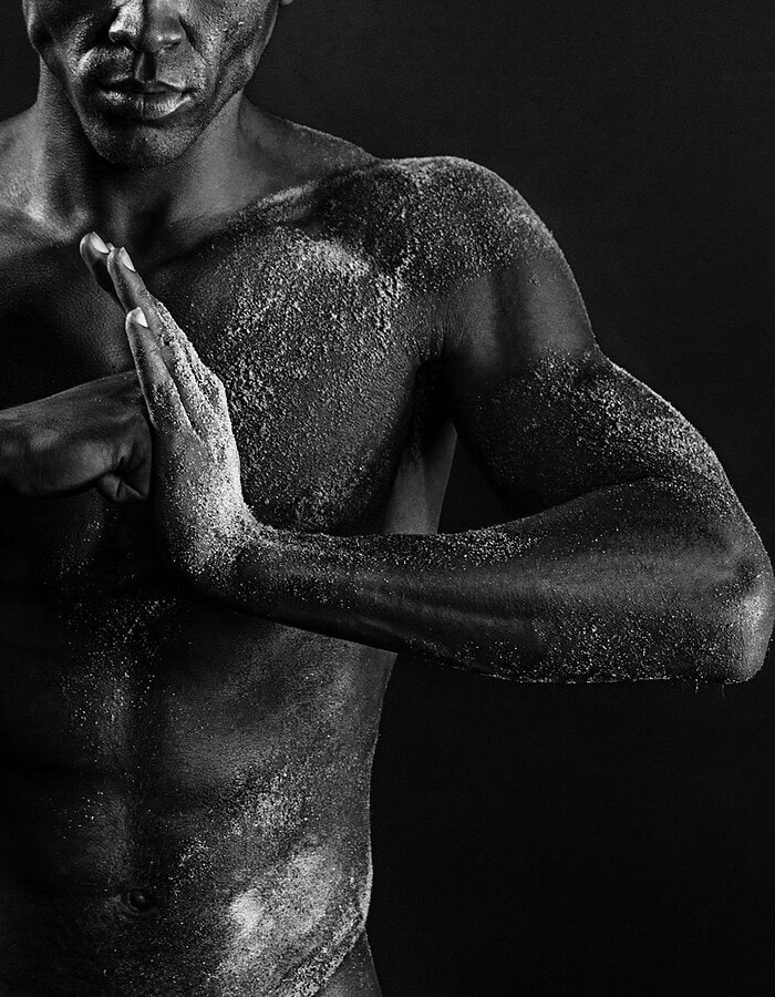 Horizontal close-up of a male model pressing his hands together across his torso