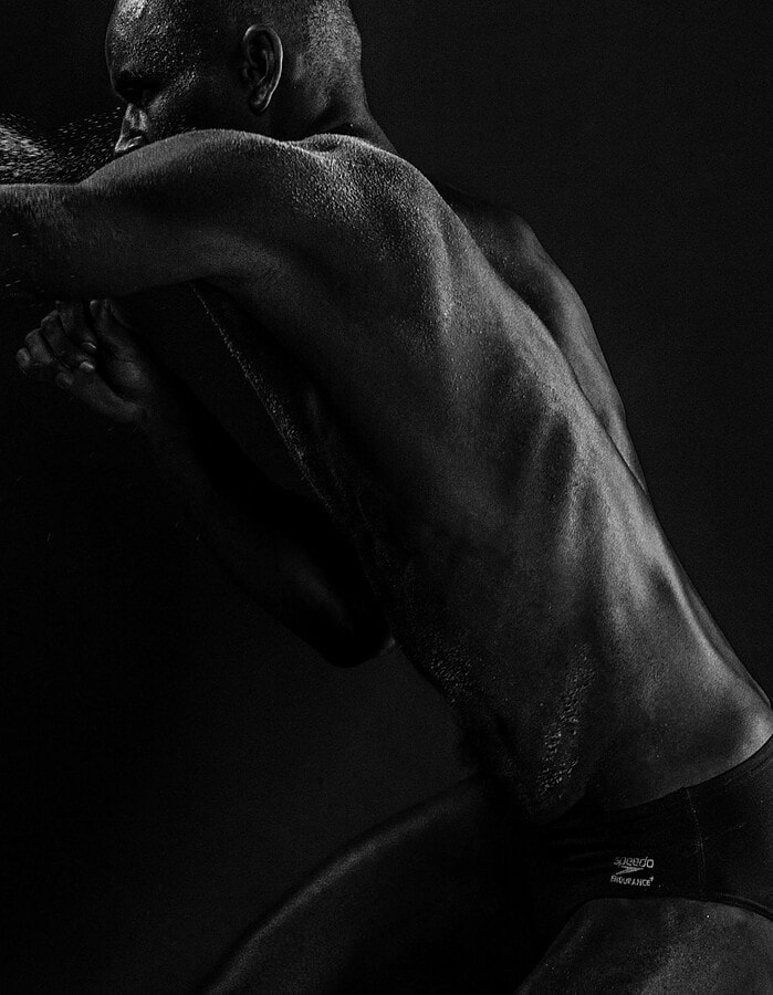 Male model extending his arm as sand moves through the air in a dark studio