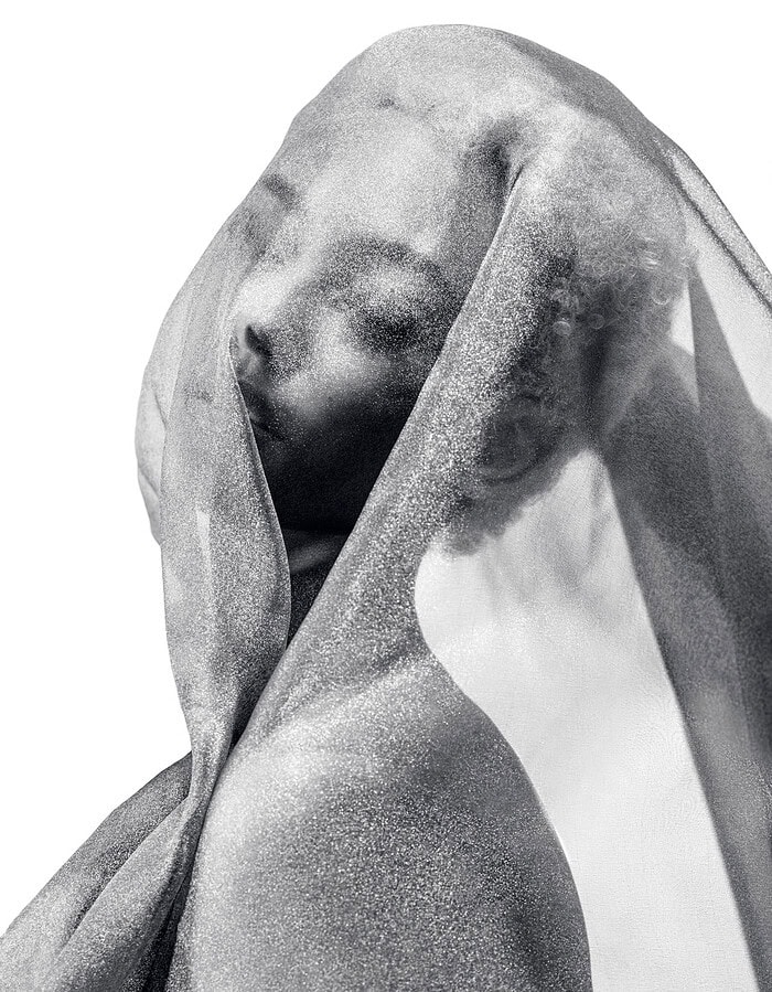 Close profile of a dancer seen through shimmering translucent fabric