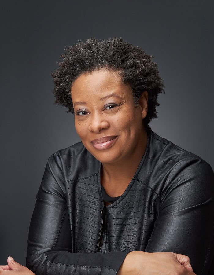 Approachable personal branding portrait of a woman in a black leather jacket with folded arms.