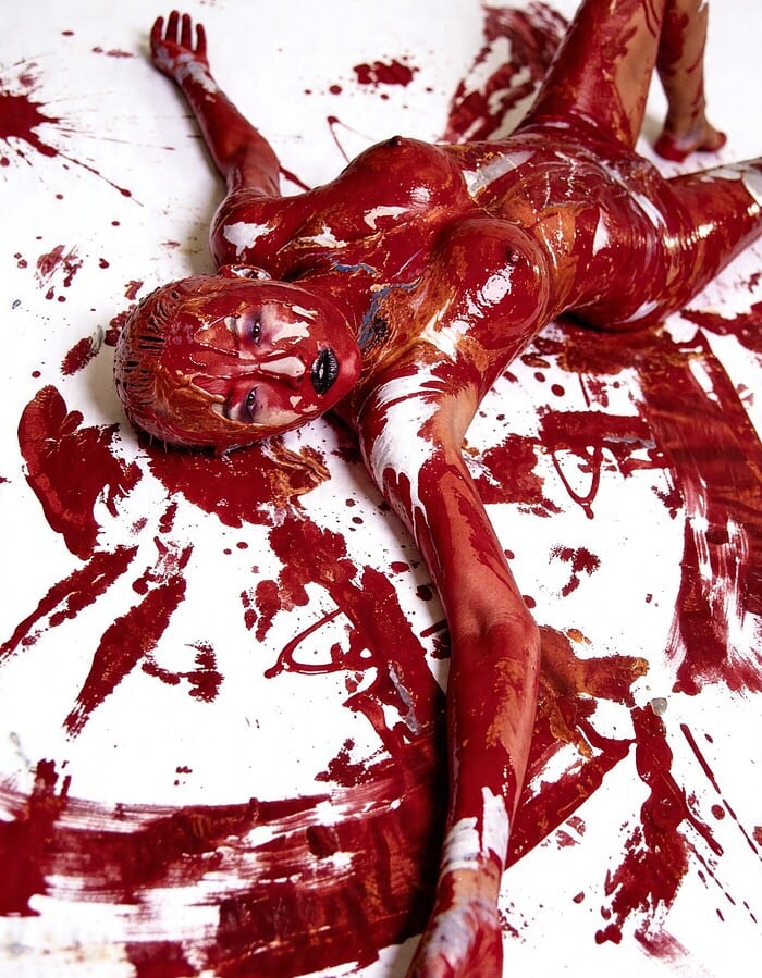 Overhead portrait of Brittany lying on white seamless surrounded by abstract red paint marks.