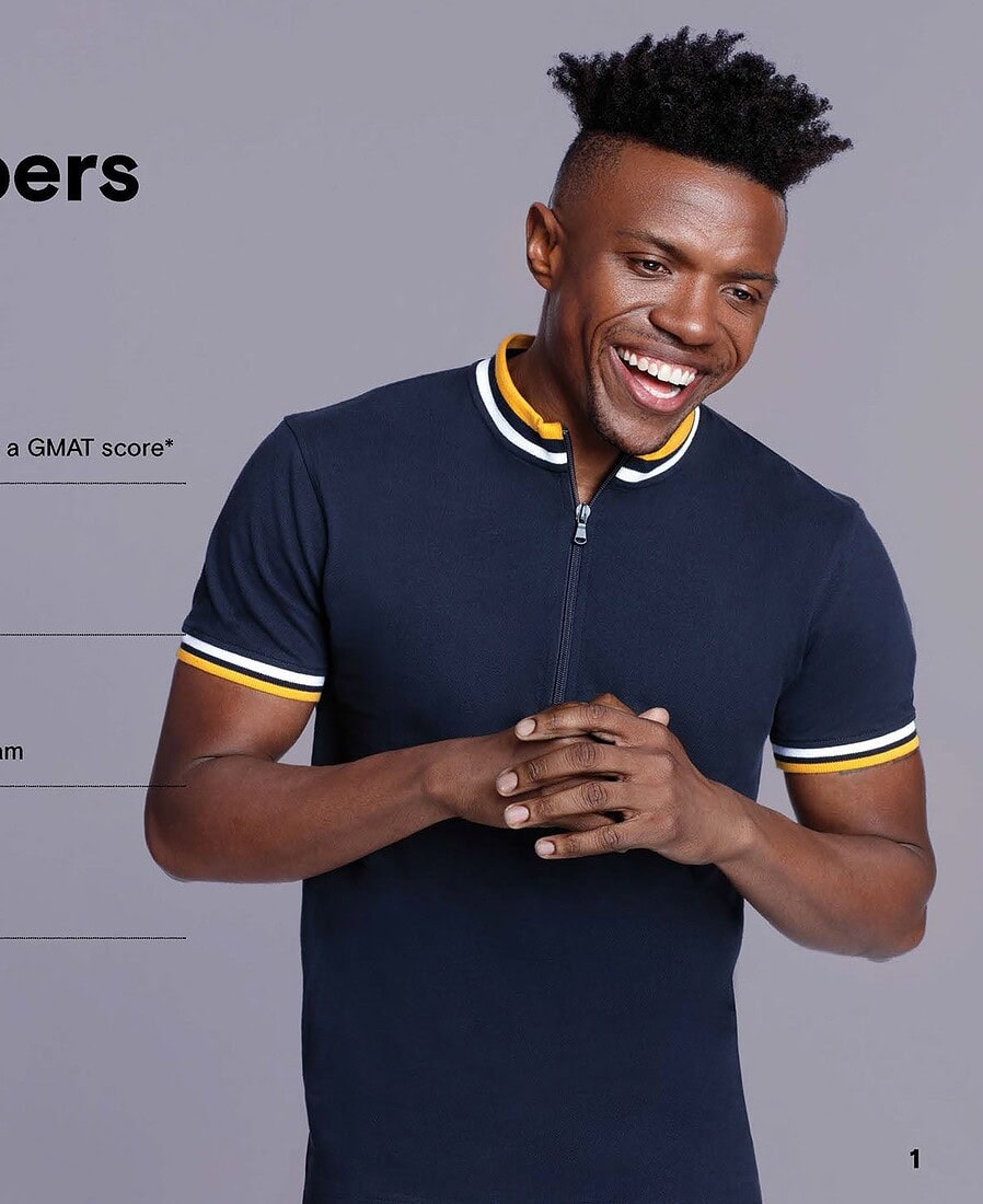 Smiling man in a dark polo shirt featured beside GMAT enrollment statistics in an advertising layout.