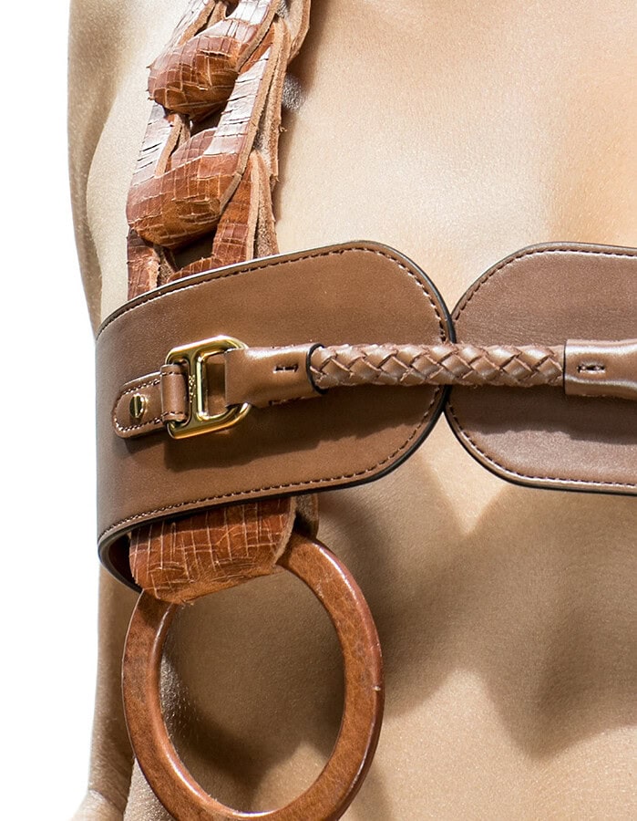 Close detail of layered brown leather belts with braided trim, gold buckles and textured straps.