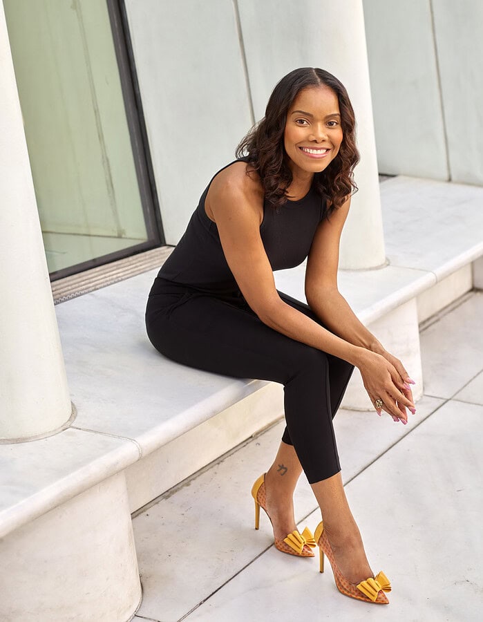 Relaxed lifestyle portrait of a woman seated among white architectural columns in New York City.