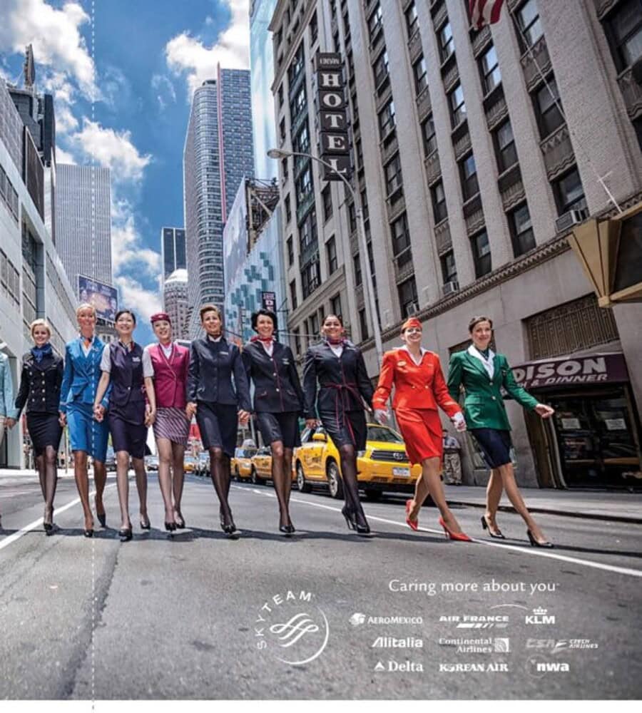SkyTeam airline cabin crew in colorful uniforms walking together on a New York City street.