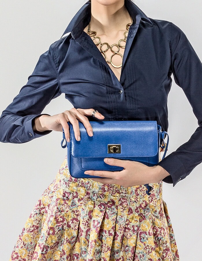 Cropped studio fashion image centered on a blue clutch, navy blouse and patterned skirt.