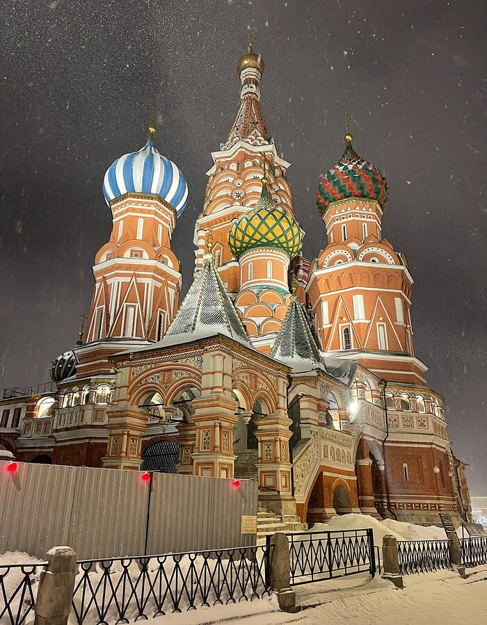 St. Basil’s Cathedral lit at night during snowfall in Moscow.