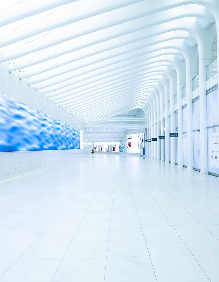 Blue wall and white architectural corridor inside the World Trade Center Oculus during COVID.