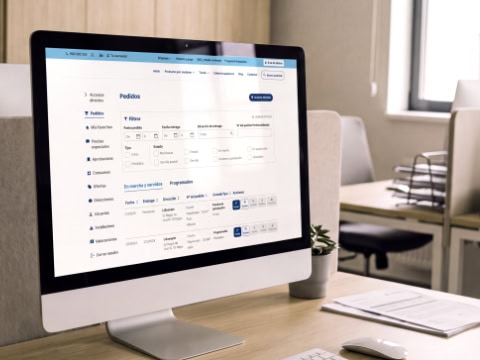 Monitor de oficina con una plataforma de gestión de pedidos en pantalla.