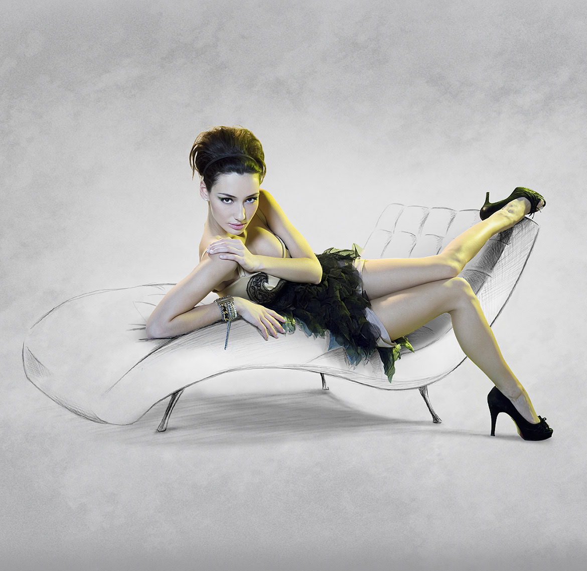 A woman in a black dress and high heels lying on a modern white sofa against a grey background.