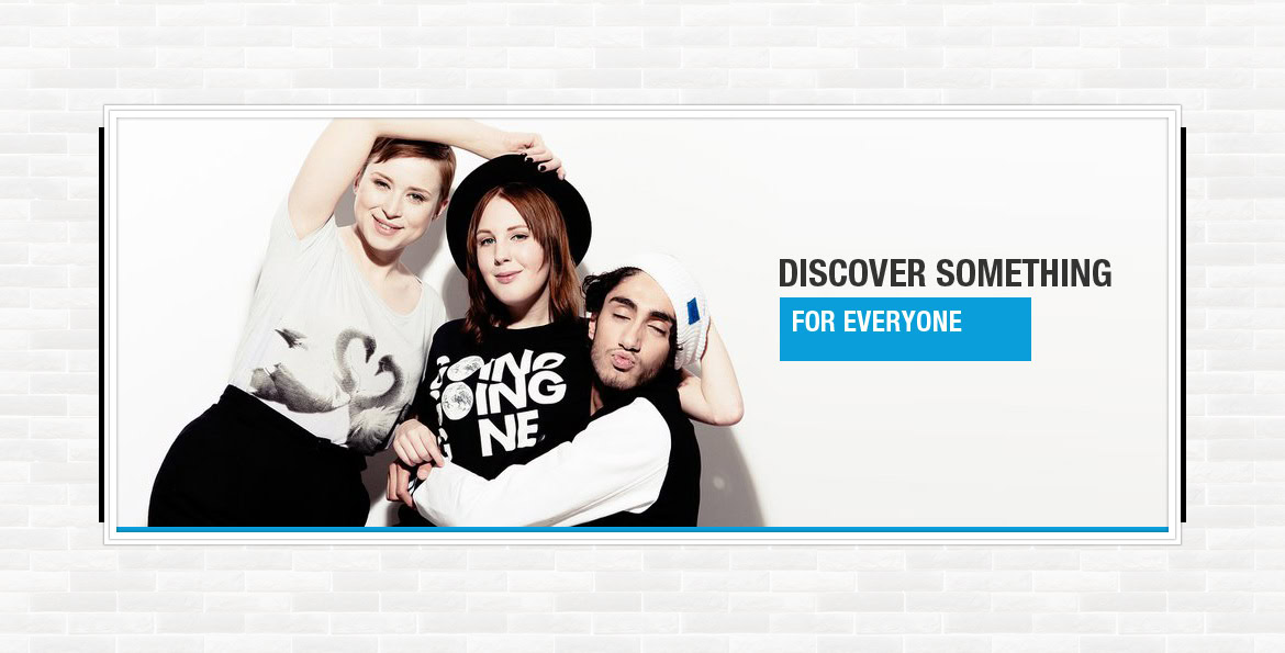 Discover a diverse group of young people smiling and posing together against a white brick wall.