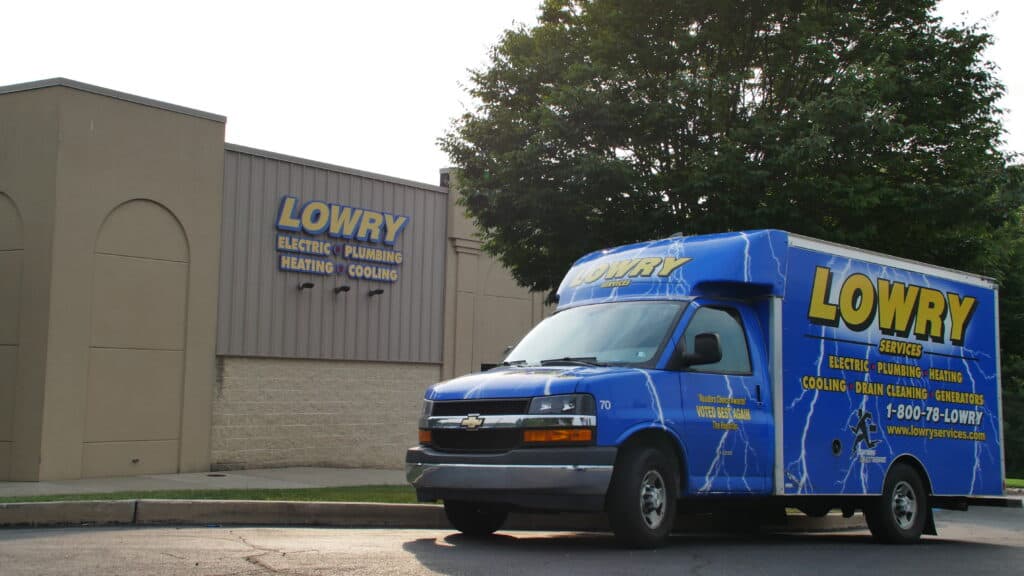 A Lowry Services van parked outside a Lowry Services building, ready to assist with electric, plumbing, heating, cooling, and related services—contact us today for expert solutions.