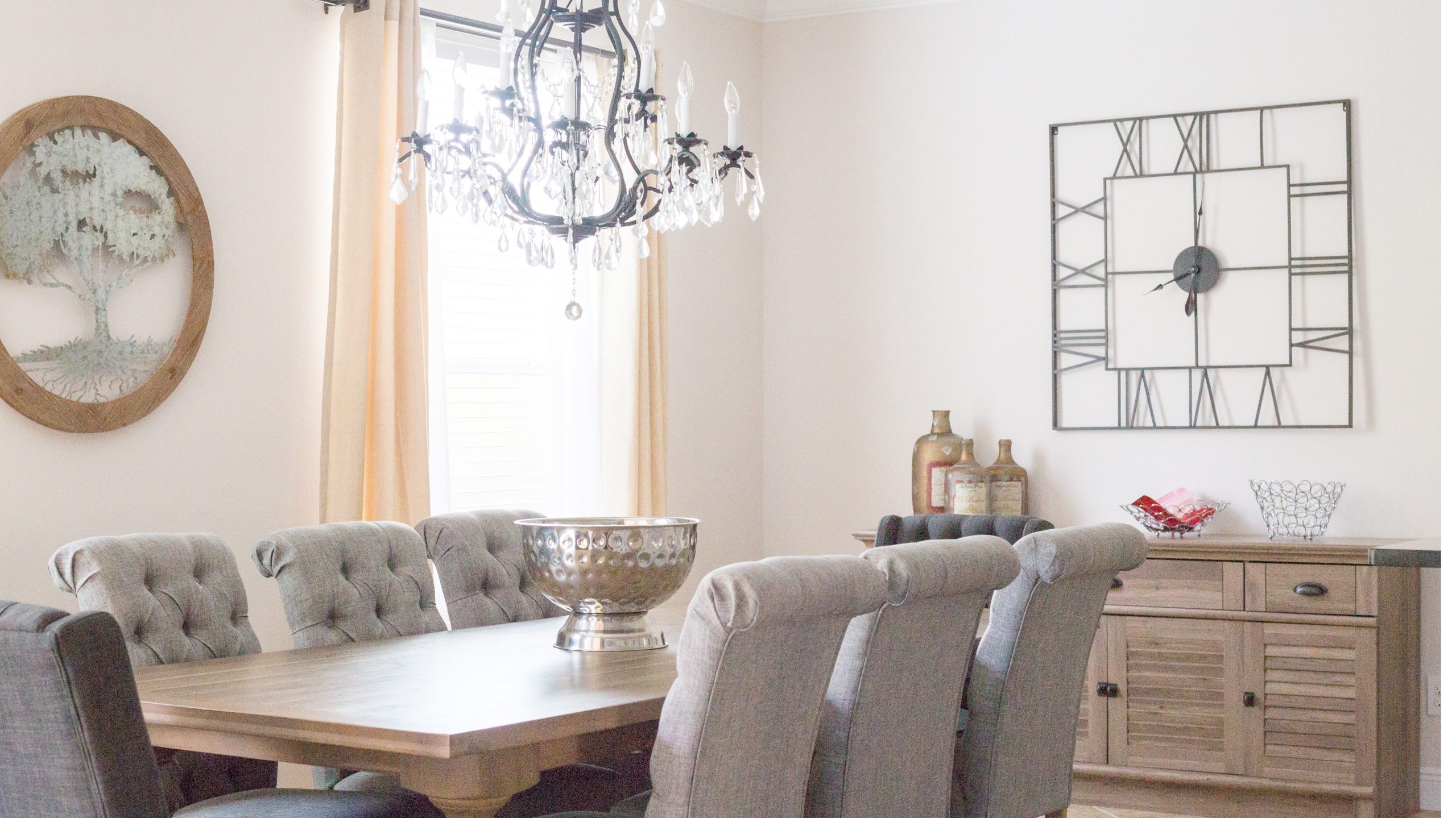 Bright dining room with a wooden table, tufted chairs, and modern wall clock.