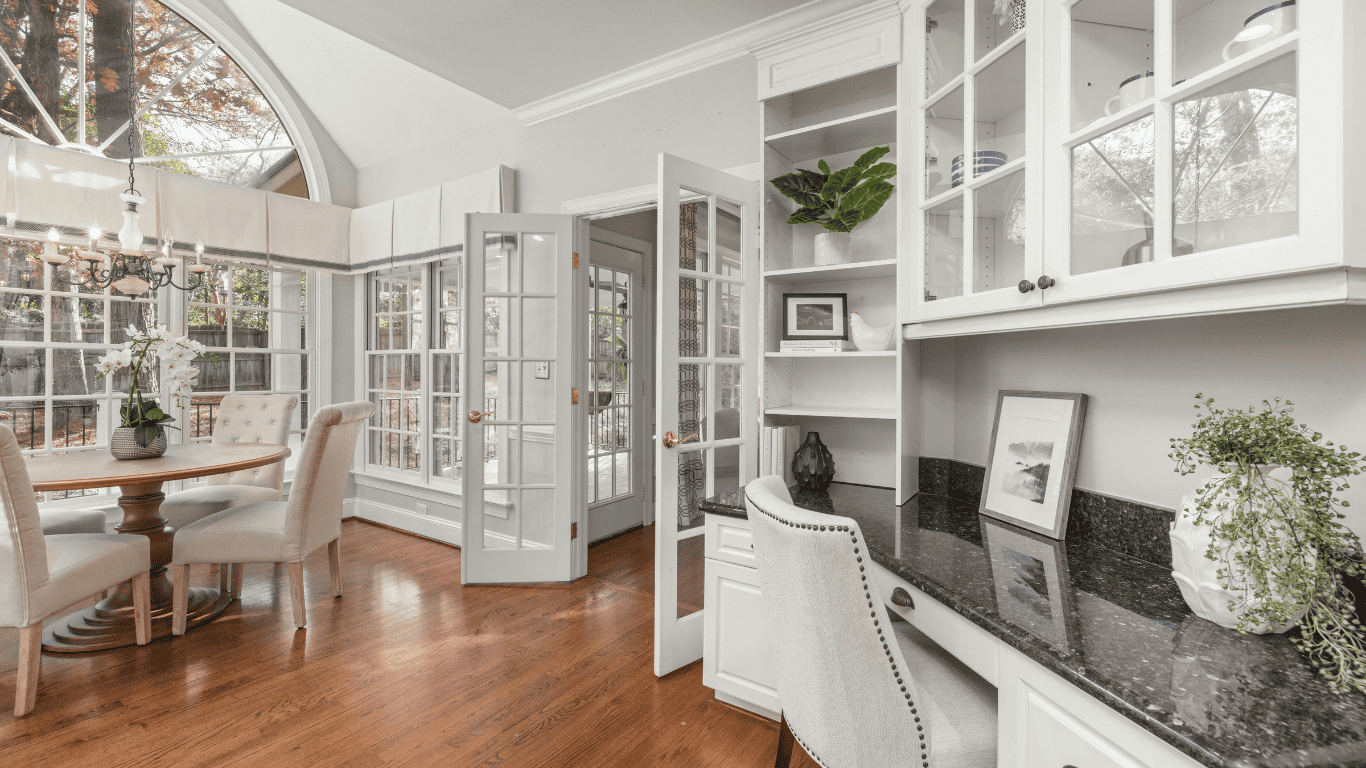 Spacious kitchen with white cabinetry, large windows, and hardwood floors.