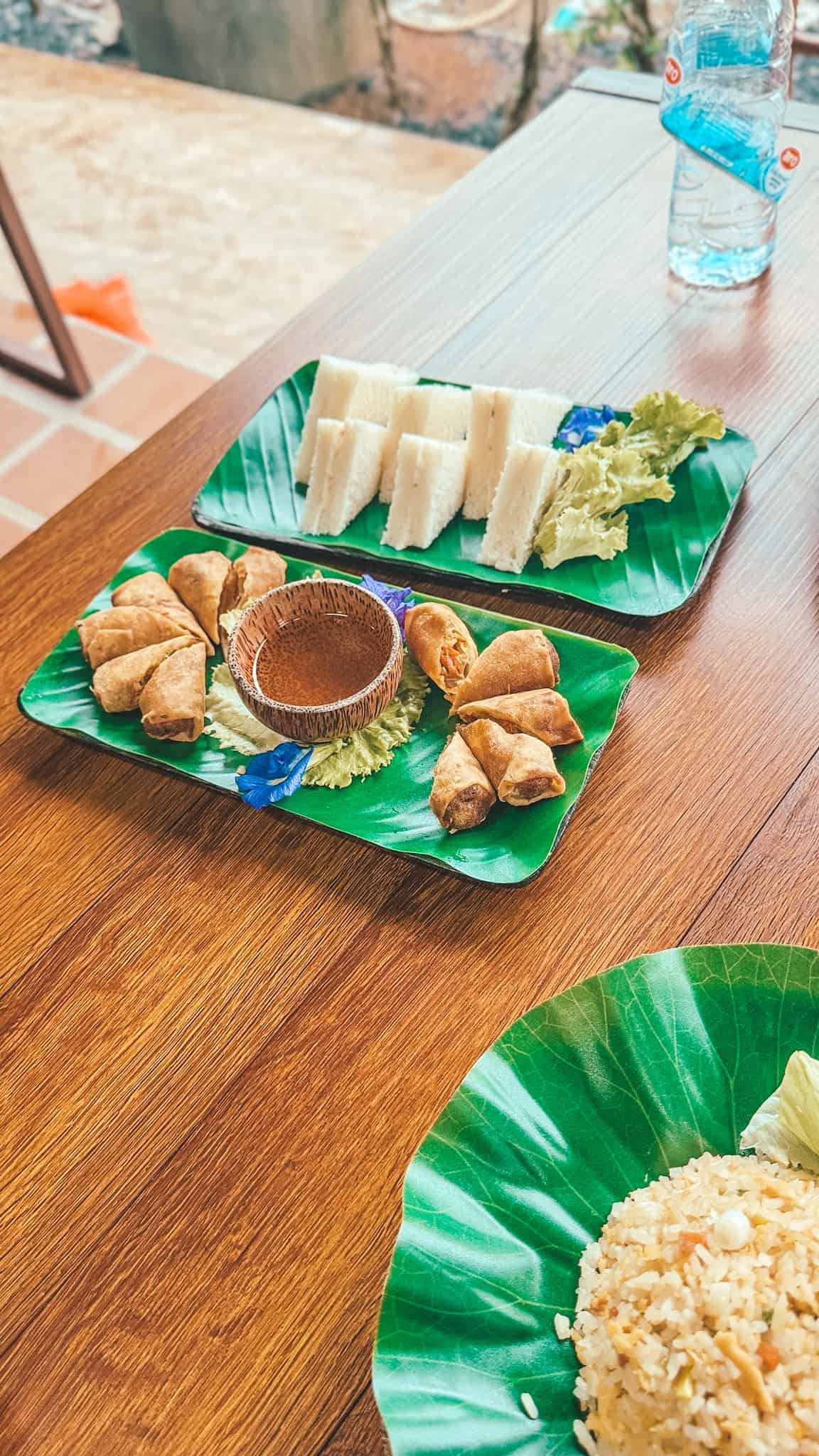 Traditional Thai snack platter with fresh vegetables and fried snacks on banana leaf plates.