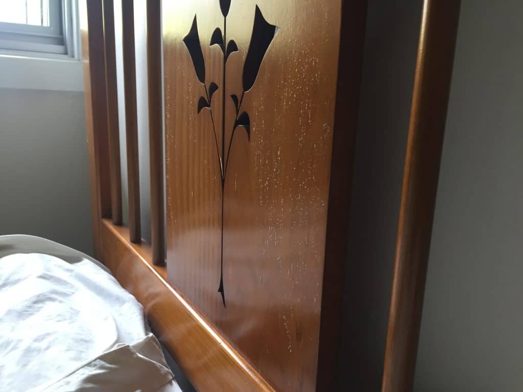 Mould growth on a wooden bedhead positioned against the wall.