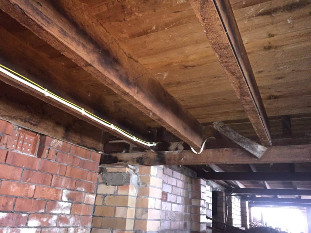 Timber subfloor beneath a home showing floor joists, brickwork and underfloor space