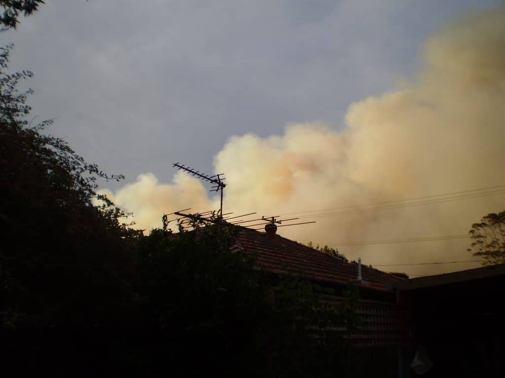Bushfire smoke visible in the sky near an Australian home