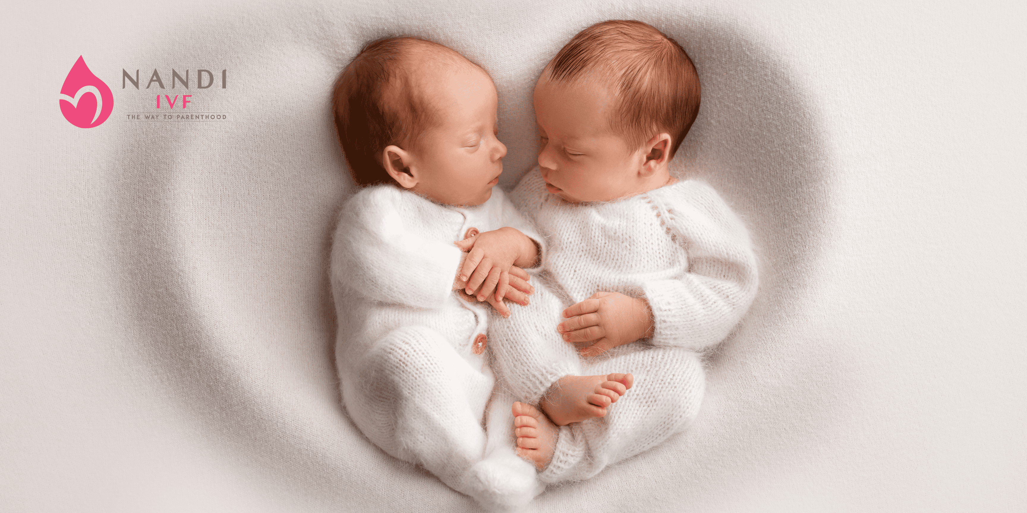 Two newborn twins sleeping peacefully on a soft blanket.