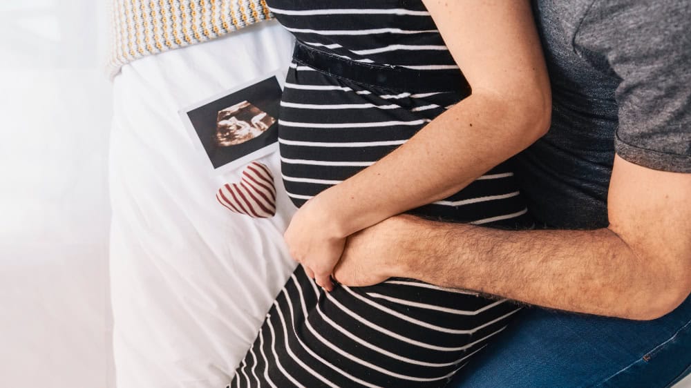 Couple holding ultrasound image of their baby.
