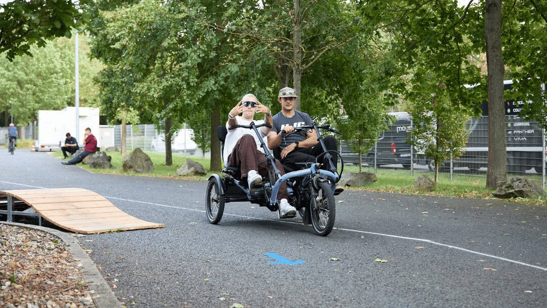Fahrrad mit E-Antrieb fährt durch den Park mit zwei Personen.