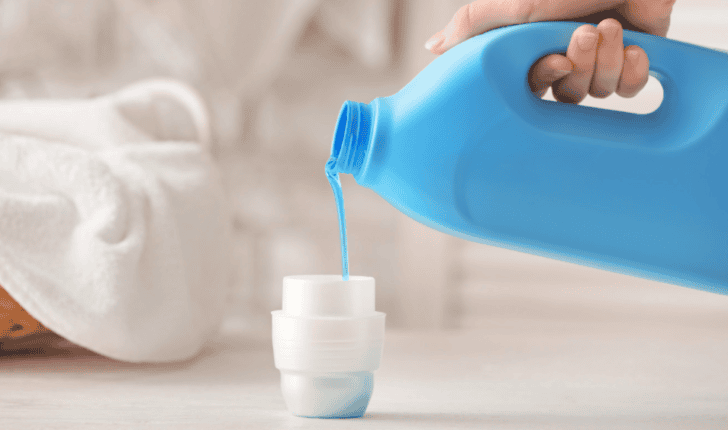 High-quality blue liquid laundry detergent being poured into a white container for washing clothes, highlighting fabric care and cleaning solutions.