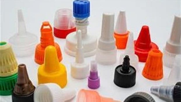 Colorful plastic bottle caps and nozzle tips for medical or cosmetic applications, arranged on a white background.