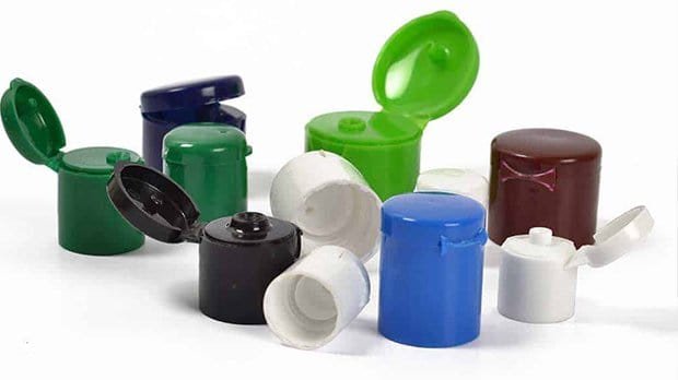Assorted plastic bottle caps and lids in various colours including green, blue, black, white, and maroon, isolated on a white background.