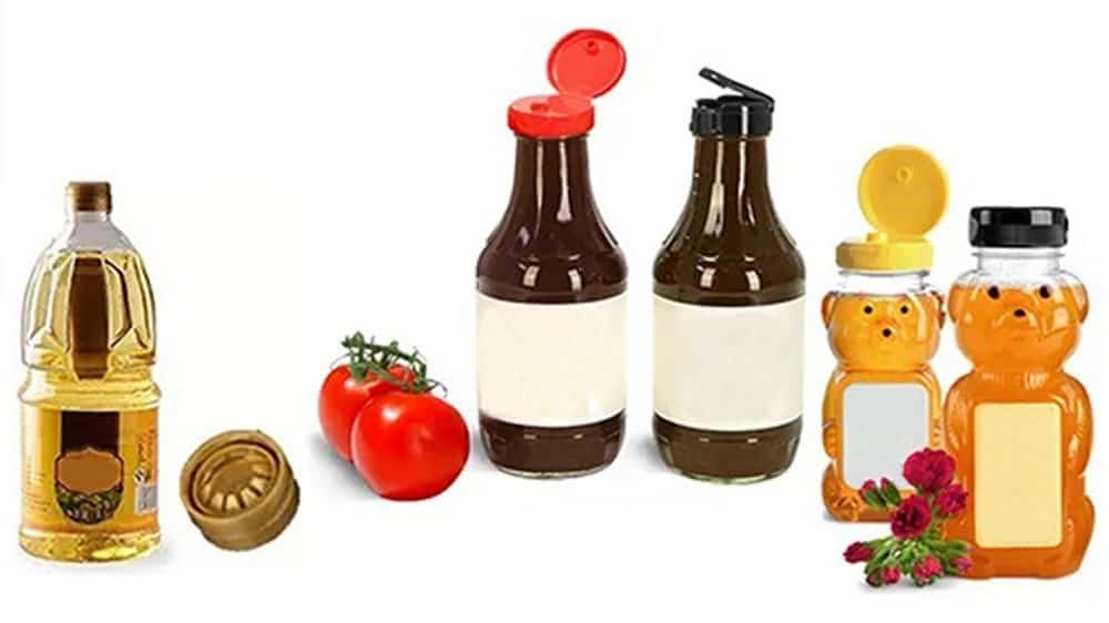 Golden cooking oil bottle, fresh tomatoes, condiment bottles with squeeze and flip caps, and cute bear-shaped honey jars with flowers, on a white background.