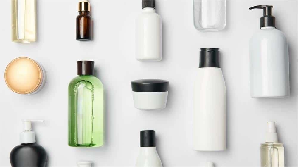 Sleek collection of cosmetic and skincare bottles and jars in various shapes and sizes, arranged on a white background, showcasing beauty and personal care products for healthy skin and hair.