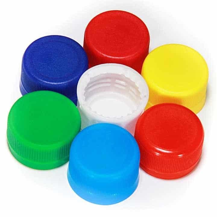 Multicoloured plastic bottle caps in red, blue, yellow, green, and white, arranged in a circle on a white background. Perfect for recycling, craft projects, or storage solutions.