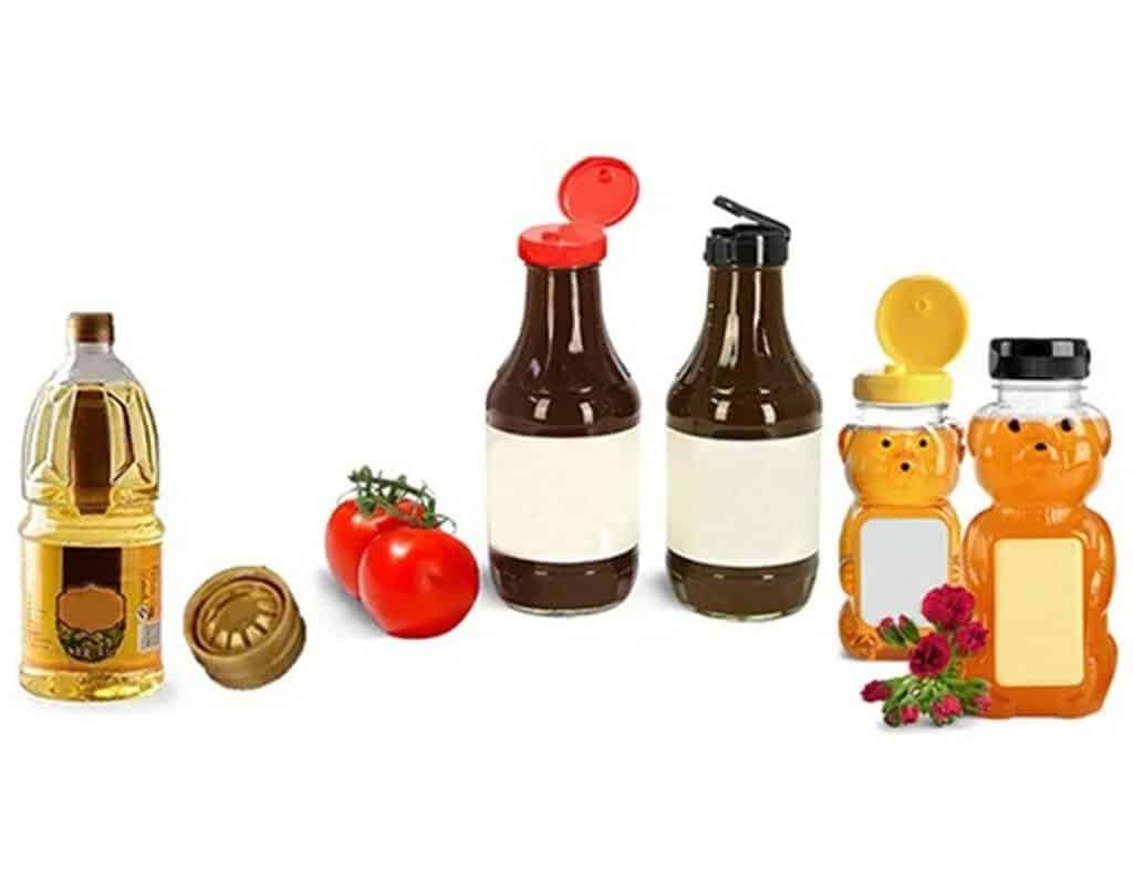 Liquid condiment bottles with caps, fresh tomatoes, and honey jars with bear-shaped lids, some flowers, on a white background. Perfect for highlighting condiments, sauces, and natural sweeteners in culinary or product images.