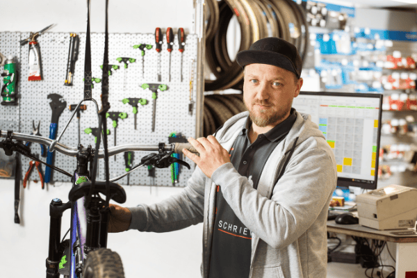 Mitarbeiter bei Rad-Sport Schriewer repariert Fahrrad im Laden.