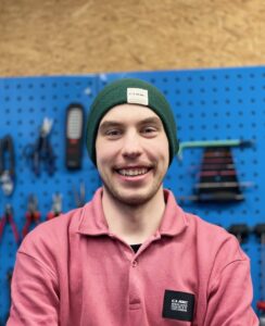 Rad & Tat Tübingen Werkstatt Junger Mann mit grüner Mütze und rosa Pullover in Werkstatt.
