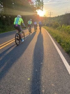 Group of cyclists riding on a rural road at sunset in Virginia.