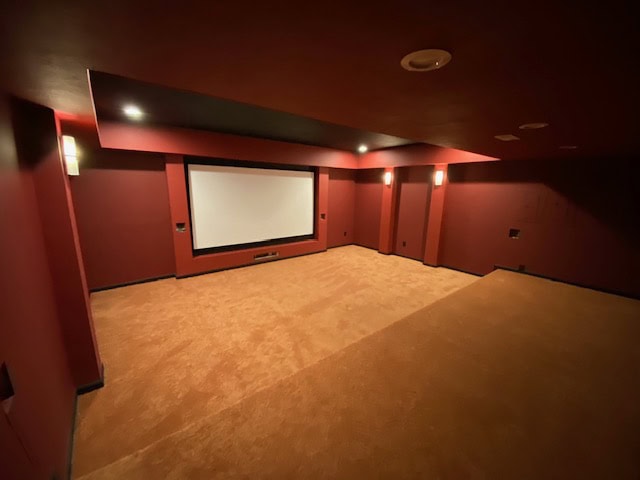 Custom home theater room with red walls and plush carpet flooring.