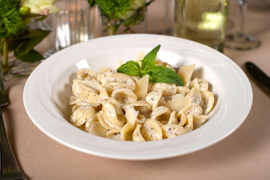 Orecchiette pasta in a creamy black pepper sauce, topped with shaved cheese and fresh basil.