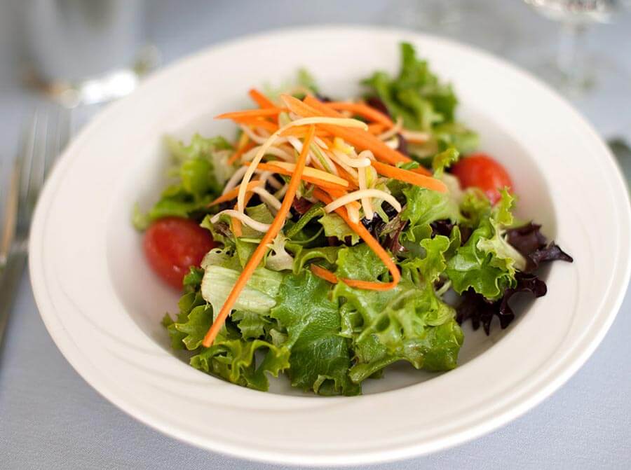 Fresh garden salad with cherry tomatoes and julienned carrots in a white bowl.