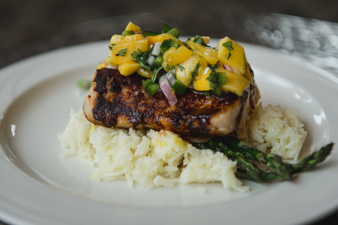 Pan-seared fish over white rice and asparagus, topped with a vibrant fresh mango salsa.