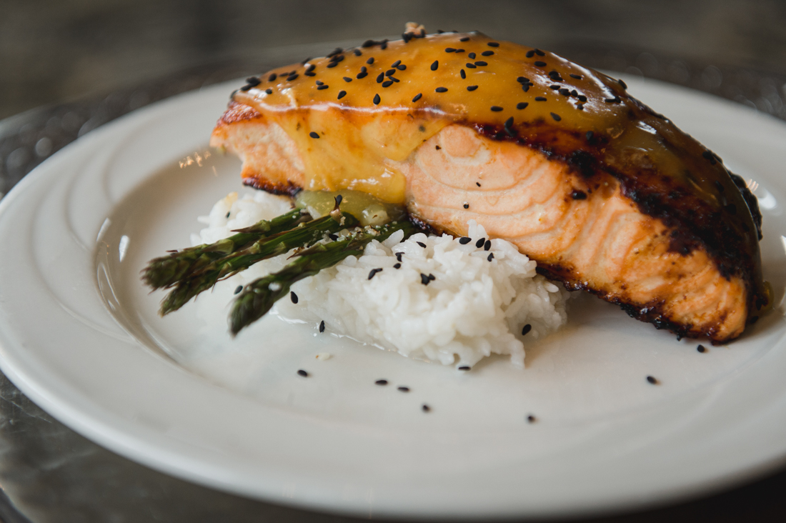 Glazed salmon fillet with black sesame seeds, served over white rice and asparagus.