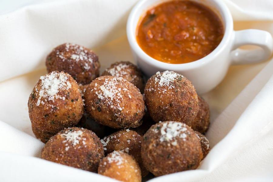 Fried meatballs sprinkled with parmesan cheese, served with a side of marinara sauce.