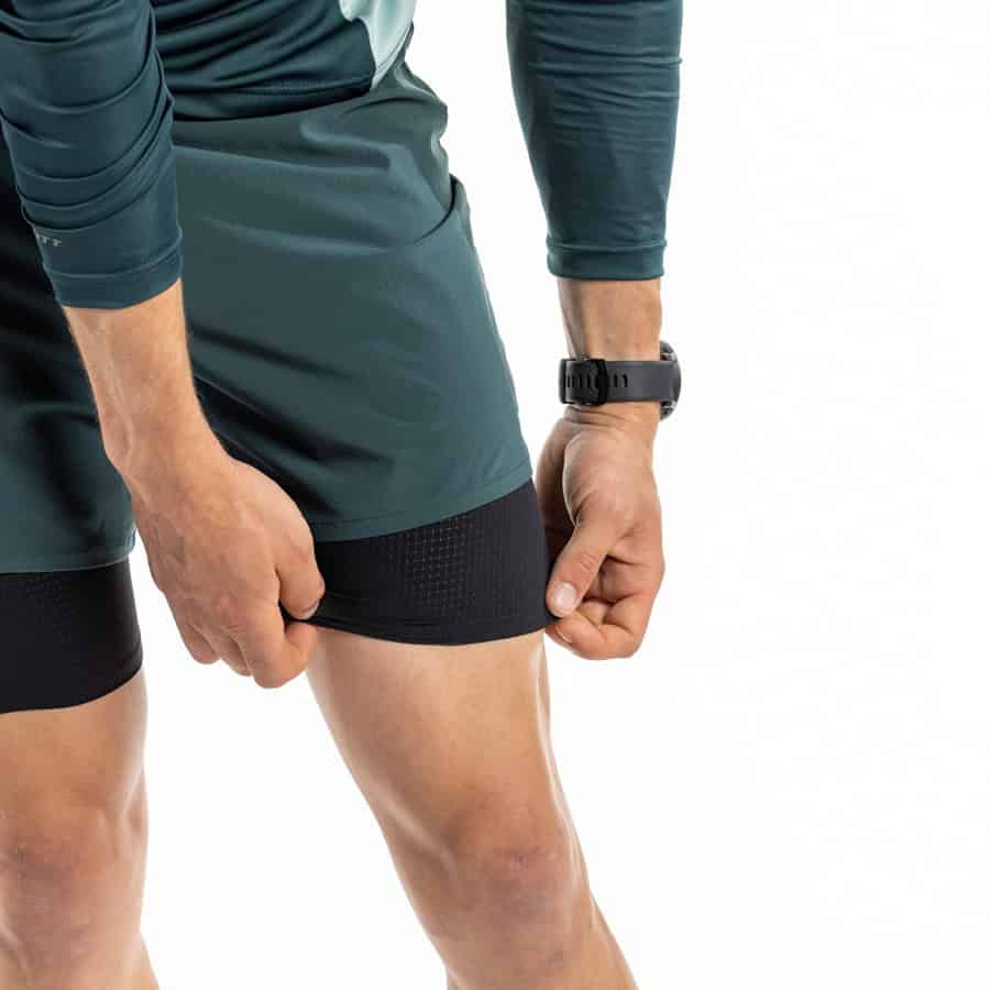 Running insights, runner adjusting compression sleeve on thigh, fitness gear, athletic performance, running apparel, training gear, injury prevention, sportswear, high-performance running equipment, endurance training, running biomechanics, sports technology, fitness tracking, sports performance analysis, marathon preparation, sports injuries, running shoes, athletic gear, sports science, performance optimisation.