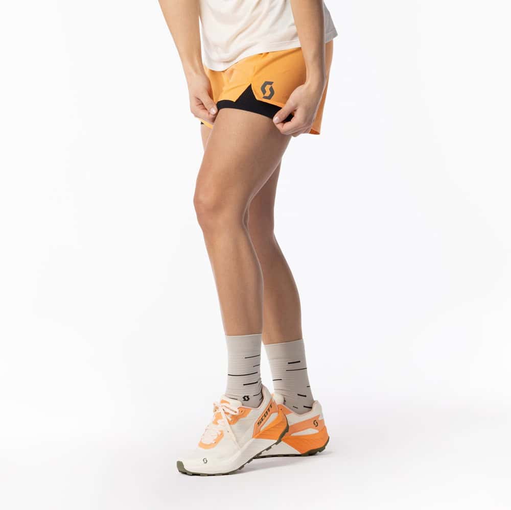 Lightweight running shoes with orange accents on a runner's feet, showcasing performance footwear for distance running and sprinting.