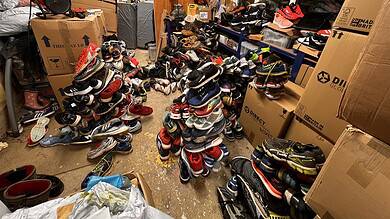 Cluttered storage room filled with organised piles of running shoes and sports gear, suitable for runners and athletes.