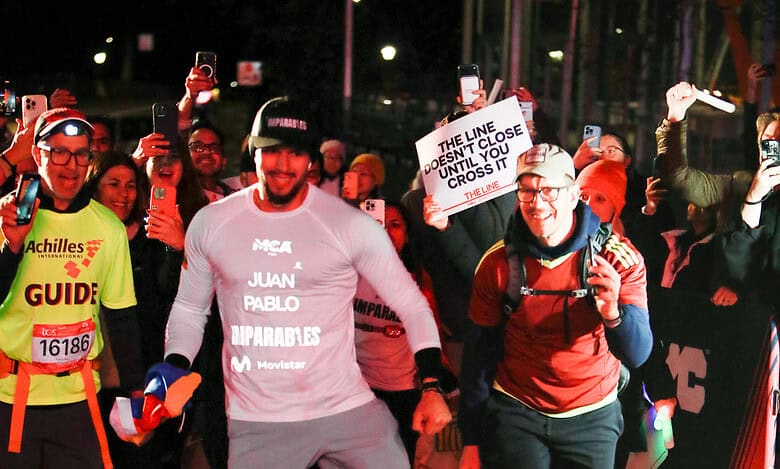 Brightly lit marathon finish line with runners and supporters, showcasing dedication and celebration at night, emphasising performance and sportsmanship in running events.